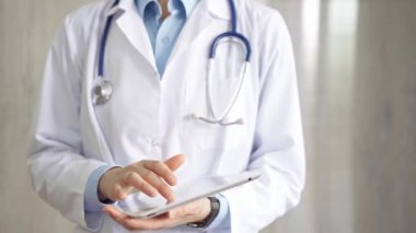 Doktor kadın laboratuvar önlüğü ve steteskop giyiyordu. Hastanede tablet bilgisayar kullanıyordu. Tıp ve bilim konsepti.