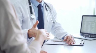 Doktor ve bir hasta el sıkışıyor. Hekim mavi gömlek ve kravatın üzerine beyaz bir tıbbi ceket giyiyor. Tıbbi hizmet.