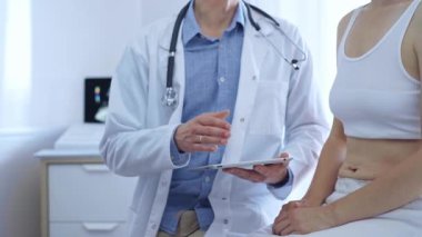 Doktor ve hasta. Doktor, hasta kadın bir şey tarif ederken tablet bilgisayar kullanıyor. İlaç ve sağlık hizmetleri.