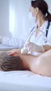 Beyaz tıbbi eldivenli doktor kadın erkek hastaya boyun ultrasonu yapıyor. Tiroid bezi muayenesi. Tıp konsepti.