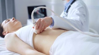 Doktor adam, beyaz tıbbi eldiven takıyor ve tıbbi kardiyoloji muayenesi için uzanan bir kadının göğsünde ultrason cihazı kullanıyor. Tıp konsepti.