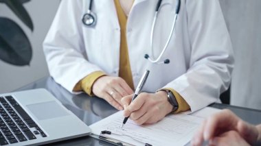 Doktor hastayla evrak işlerini hallediyor. Formları olan doktorların elleri bilgisayara bilgi aktarıyor. İlaç ve sağlık hizmetleri kavramı.