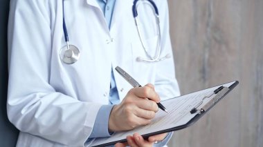 Sağlık sigortası uzmanı doktor bir panoya tıbbi kayıtlar yazıyor. İş yerinde tanınmayan bir kadın doktor var. İlaç ve eczane.
