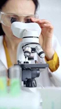 Woman scientist using microscope in laboratory. Microbiology science concept. clipart