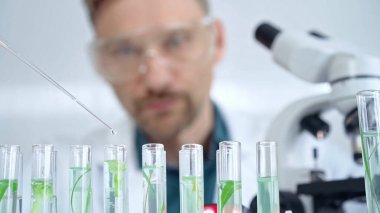 Güvenlik gözlüklü bir araştırmacı laboratuvar borularıyla laboratuvar ekipmanlarına yakın çekim yapıyor. Bilim ve tıp.