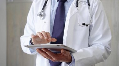 Laboratuvar önlüğü ve steteskop giyen doktor hastanede tablet bilgisayar kullanıyor. Tıp ve Bilim.