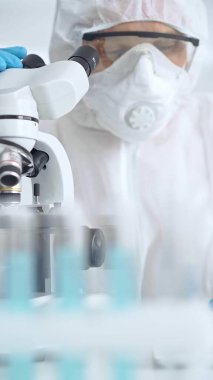 Bir laboratuvar ortamında mikroskop kullanarak örnekleri analiz eden bilim adamı..