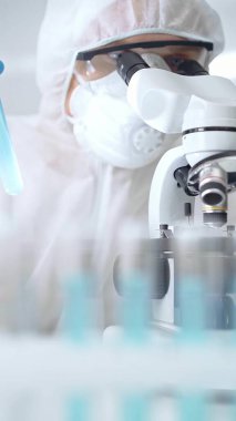 Laboratuvar ortamında mikroskopla örnekleri analiz eden ve analiz eden bir bilim adamı. Bilim konsepti.