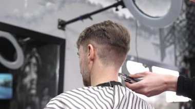 Profesyonel berber erkek müşterinin saç çizgisini traş ediyor. Hızlı bir berber dükkanında ustura kullanıyor. Modern bir saç stilini ustalıkla ve ustalıkla yapıyor.