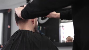 Profesyonel berber, erkek müşterilerin saçlarını makas ve tarakla buduyor. Çağdaş kuaförde modern saç stili yaratıyor..
