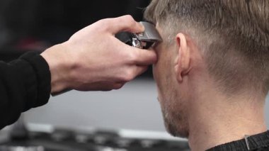 Berberlerin ellerini elektrikli jilet kullanarak kapamak, profesyonel berber dükkanı ortamında erkek müşterilerin kafalarında kusursuz saç kesimi yaratmak, erkek tımarında yetenek ve hassasiyet sergilemek.