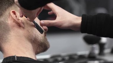 Berberlerin elleri jilet gibi keskin, müşterilerin sakallarını dikkatlice traş eden profesyonel berber dükkanlarında, hassasiyet ve beceri gösteriyorlar.