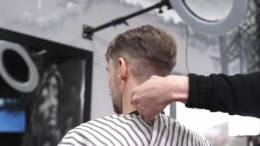 Profesyonel berber erkek müşterinin saç çizgisini traş ediyor. Hızlı bir berber dükkanında ustura kullanıyor. Modern bir saç stilini ustalıkla ve ustalıkla yapıyor.