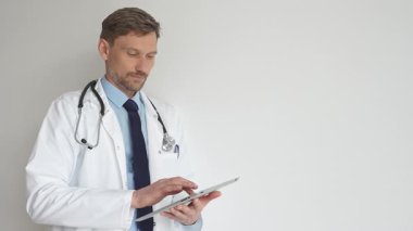 Kendine güvenen erkek doktor kolları çapraz duruyor, steteskop ve beyaz önlük giyiyor. Düşünceli bir şekilde, tıp alanında profesyonelliği ve uzmanlığı somutlaştırıyor. İlaç ve sağlık hizmetleri