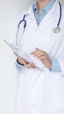 Mavi bluzun üzerine steteskop ve beyaz önlük giyen kimliği belirsiz kadın doktor tıbbi uzmanlığı ve hasta bakımını temsil eden siyah bir panoya yazı yazıyor. Tıp konsepti.