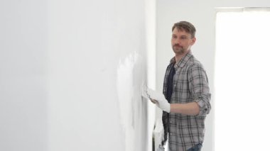 İnşaat işçisi beyaz duvara alçı yayıyor, ev yenileme projesi sırasında koruyucu eldiven takıyor, profesyonel beceri ve odaklanma ile çalışıyor.