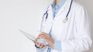 Mavi bluz ve steteskop üzerine beyaz önlük giyen kimliği belirsiz kadın doktor dijital tablet kullanıyor. Bu da tıpta yenilikçi sağlık uygulamaları olduğunu gösteriyor. Sağlık ve Tıp Konsepti.