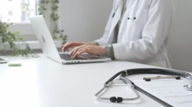 Stetoskop ve tıbbi kayıtlar doktorun karşısındaki masada. Bilgisayarında tıbbi bir büro var. İnternet üzerinden sağlık hizmeti ya da teletıp hizmeti sunuyor. Tıp konsepti.