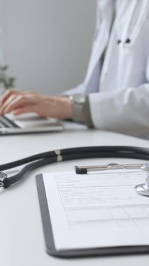 Stetoskop ve tıbbi kayıtlar doktorun karşısındaki masada. Bilgisayarında tıbbi bir büro var. İnternet üzerinden sağlık hizmeti ya da teletıp hizmeti sunuyor. Tıp konsepti.