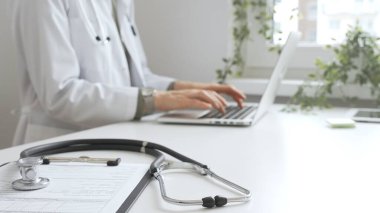 Tıbbi kayıtlar üzerinde steteskop var. Doktorun bilgisayarında yazdığı bilgisayarın karşısında duruyor. Bu da sağlık hizmeti ya da teletıp hizmetlerini gösteriyor. Tıp konsepti.