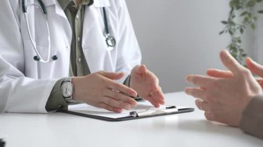 Doktor, tıbbi muayene sırasında hastaya el kol hareketi yaparak teşhisi açıklıyor. İlaç ve sağlık hizmetleri kavramı.