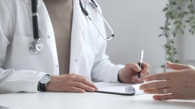 Doktor, parlak ve modern bir klinikteki muayene sırasında hasta sağlığıyla ilgili endişeleri dinliyor ve reçete yazıyor. İlaç ve sağlık hizmetleri kavramı.