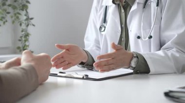 Doktor, tıbbi muayene sırasında hastaya el kol hareketi yaparak teşhisi açıklıyor. İlaç ve sağlık hizmetleri kavramı.