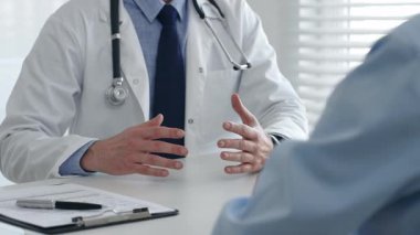 Doktor, parlak bir muayenede hastaya teşhisi açıklarken elleriyle el hareketi yapıyor. İlaç ve sağlık hizmetleri kavramı