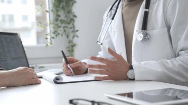 Doktor adam, tıbbi muayenede kadın hastaya teşhis koymayı anlatıyor. Elleriyle işaret ediyor. İlaç ve sağlık hizmetleri kavramı