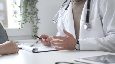 Doktor adam, tıbbi muayenede kadın hastaya teşhis koymayı anlatıyor. Elleriyle işaret ediyor. İlaç ve sağlık hizmetleri kavramı