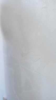 Duvar, son malayı kullanmak için bekliyor. Alçıyı dikkatlice uygulamak, ev yenileme konusunda uzmanlık göstermek için..