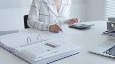 Muhasebecinin not aldığı, muhasebe, finans ve vergi hazırlıklarını vurguladığı mali dökümanlarla ilgili bir hesap makinesini kapatın. Ticarette denetim ve vergiler.