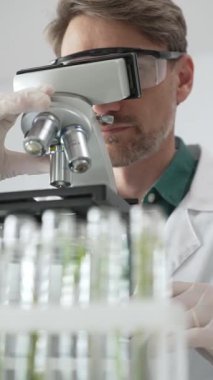 Koruyucu ekipman araştırmacısı steril bir laboratuvar ortamında mikroskopla numuneleri analiz ediyor. Tıp, sağlık ve bilim konsepti.