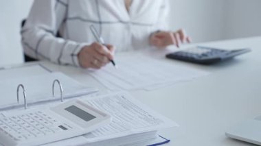 Muhasebecinin not aldığı, muhasebe, finans ve vergi hazırlıklarını vurguladığı mali dökümanlarla ilgili bir hesap makinesini kapatın. Ticarette denetim ve vergiler.