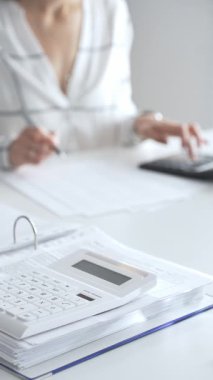 Muhasebecinin not aldığı, muhasebe, finans ve vergi hazırlıklarını vurguladığı mali dökümanlarla ilgili bir hesap makinesini kapatın. Ticarette denetim ve vergiler.