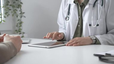 Dijital test sonuçlarını hastayla inceleyen kadın doktor, modern klinik ortamdaki tıbbi bulguları, sağlık teknolojisi etkileşimini tartışıyor. İlaç ve sağlık hizmetleri kavramı