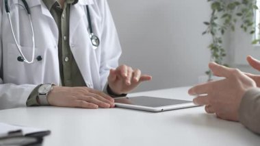 Dijital test sonuçlarını hastayla inceleyen kadın doktor, modern klinik ortamdaki tıbbi bulguları, sağlık teknolojisi etkileşimini tartışıyor. İlaç ve sağlık hizmetleri kavramı