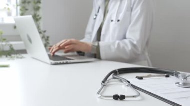 Stetoskop ve tıbbi kayıtlar doktorun karşısındaki masada. Bilgisayarında tıbbi bir büro var. İnternet üzerinden sağlık hizmeti ya da teletıp hizmeti sunuyor. Tıp konsepti.