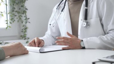 Doktor adam, tıbbi muayenede kadın hastaya teşhis koymayı anlatıyor. Elleriyle işaret ediyor. İlaç ve sağlık hizmetleri kavramı