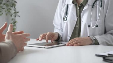 Dijital test sonuçlarını hastayla inceleyen kadın doktor, modern klinik ortamdaki tıbbi bulguları, sağlık teknolojisi etkileşimini tartışıyor. İlaç ve sağlık hizmetleri kavramı