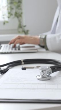 Stetoskop ve tıbbi kayıtlar doktorun karşısındaki masada. Bilgisayarında tıbbi bir büro var. İnternet üzerinden sağlık hizmeti ya da teletıp hizmeti sunuyor. Tıp konsepti.