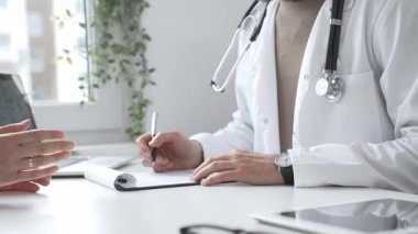 Doktor, parlak ve modern bir klinikteki muayene sırasında hasta sağlığıyla ilgili endişeleri dinliyor ve reçete yazıyor. İlaç ve sağlık hizmetleri kavramı.