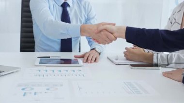 İş anlaşmasını sonuçlandıran profesyonel meslektaşlar, ellerini konferans masasına dijital cihazlar ve sözleşmeyle kenetleyerek başarılı bir kurumsal pazarlığın sinyallerini veriyorlar. El sıkışın.