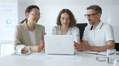 Business team collaborating on a project, analyzing data on a laptop during a productive office meeting, fostering teamwork and strategic planning