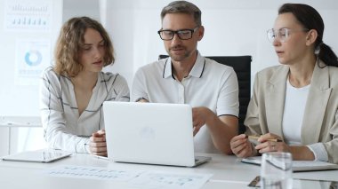Professional team analyzing data on laptop, sharing insights during collaborative office meeting, highlighting workplace synergy and strategic planning. Business people concept.