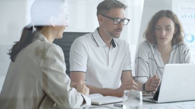 Professional team working together, reviewing digital analytics on laptop screen while strategizing corporate project details in modern workplace environment. Business people concept.