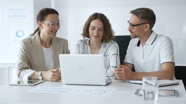 Business team collaborating on a project, analyzing data on a laptop during a productive office meeting, fostering teamwork and strategic planning