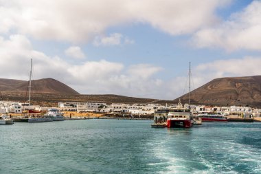Caleta del Sebo, Spain - April 30, 2022: Small harbor with touristic ferries commuting people between La Graciosa and Lanzarote, Canary Islands