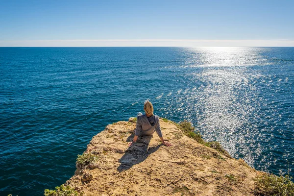 若い女性の背中の崖の上に座っているアルガルヴェのマリナビーチで大西洋の美しさに浸漬 ポルトガル — ストック写真