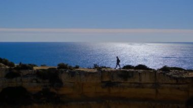 Portekiz, Algarve 'deki Marinha Sahili' nde uçurumların tepesinde yürüyen bir kadın.